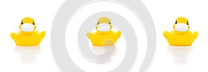 Cute yellow rubber ducks in face masks on white background, concept of social distancing flu prevention