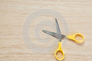 Cute yellow scissors on wooden background for craft work