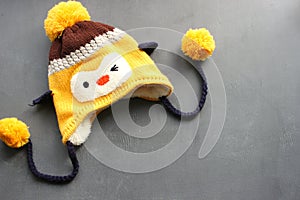 Cute yellow winter hat with bells, a Cup of tea and viburnum berries on a gray grunge background