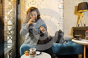 Cute young adult woman eating sweets and drinking coffee