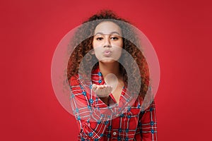 Cute young african american girl in pajamas homewear posing while resting at home isolated on red background in studio