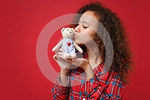 Cute young african american girl in pajamas homewear posing while resting at home isolated on red wall background. Relax