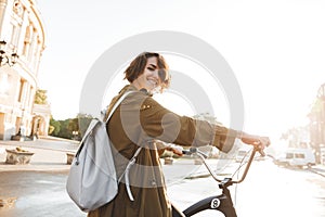 Cute young amazing woman walking outdoors in park with bicycle beautiful spring day