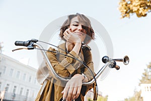 Cute young amazing woman walking outdoors in park with bicycle beautiful spring day