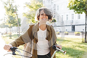 Cute young amazing woman walking outdoors in park with bicycle beautiful spring day