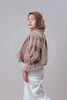 Cute young Asian muslim woman in hijab light clothes posing  on gray background