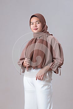 Cute young Asian muslim woman in hijab light clothes posing isolated on gray background