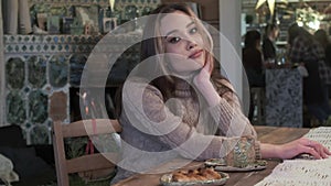 Cute young asian pretty girl sitting at table, having coffee with bun, smiling