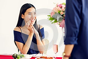 A cute young and beautiful long hair Asian woman feels shy when the man gives her rose bouquet