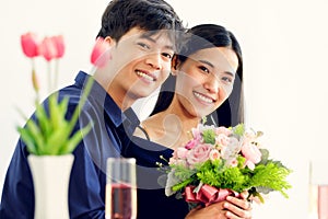 A cute young and beautiful long hair Asian woman feels shy when the man gives her rose bouquet