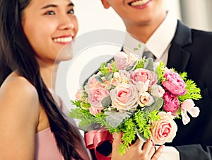 A cute young and beautiful long hair Asian woman feels shy when the man gives her rose bouquet