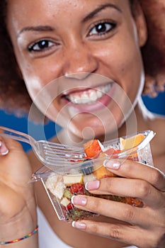 Cute young Black woman eating a fresh fruit salad