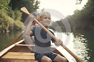 Cute young boy canoeing on the lake with his dad