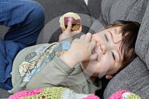 cute young boy eating an apple on the couch