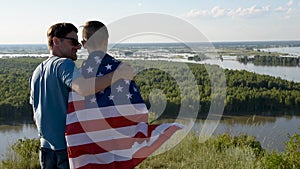 Cute young boy and his father holding aloft the American flag
