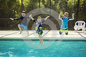 Cute young boys jumping into a swimming pool while on a fun vacation