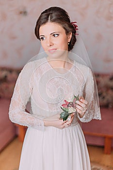 Cute young bride at home in white wedding dress, preparations concept. Portrait of tender girl in gown