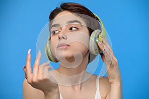 Cute young brunette listening to music using bluetooth wireless headphones