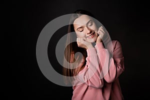 Cute young brunette in a pink hoodie, portrait on a black .