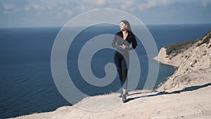 Cute young caucasian girl athlete and unbuttoning a jacket standing on seashore