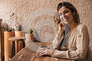 Cute young caucasian girl smiles teeth looking at camera sitting at table with coffee.