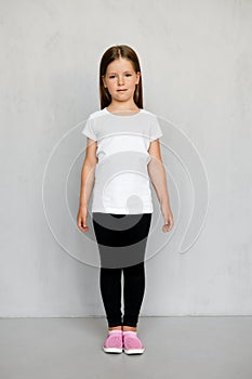 Cute young child with long hair in white t-shirt and black sweatpants