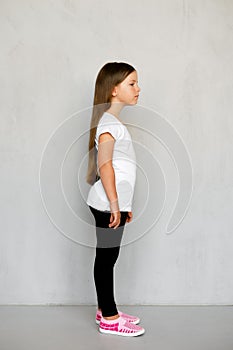 Cute young child with long hair in white t-shirt and black sweatpants