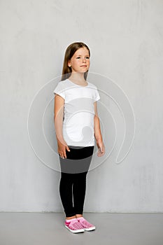 Cute young child with long hair in white t-shirt and black sweatpants