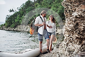 Cute young and couple on river background. A guy and a girl with backpacks are traveling by boat. Traveler summer