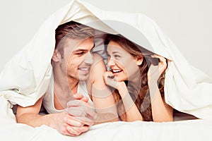 Cute young couples smiling under blanket