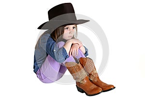 Cute young cowgirl sitting with her knees up