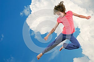 Cute young dancer girl jumping against bue sky