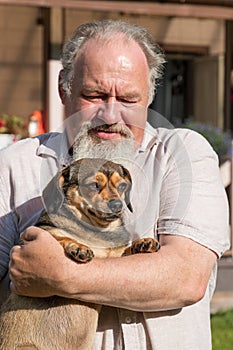 Cute young female dog mixed purebred pug and dachshund in the arms happy elderly man