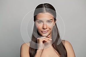 Cute young female face close up. Pretty woman with clean healthy smooth skin on grey background, skincare concept