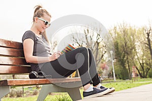 Cute young female sitting on bench and relaxing outside