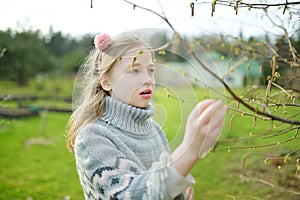 Cute young girl admiring fresh new soft buds sitting on chestnut tree branches