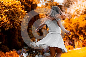 Cute young girl dancing in a park in autumn