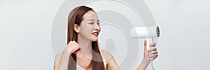 A cute young girl dries her beautiful long silky hair with a hair dryer. Banner