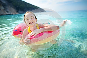 Cute young girl floating on toy ring at Myrtos beach, the most famous and beautiful beach of Kefalonia, a large coast with