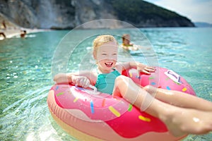 Cute young girl floating on toy ring at Myrtos beach, the most famous and beautiful beach of Kefalonia, a large coast with