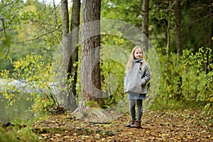 Cute young girl having fun on beautiful autumn day in a forest. Active family leisure with kids