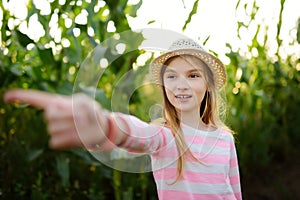 Cute young girl having fun in a corn maze field during autumn season. Games and entertainment during harvest time