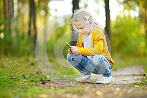 Cute young girl having fun during forest hike on beautiful summer day. Child exploring nature