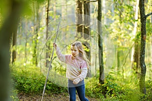 Cute young girl having fun during forest hike on beautiful summer day. Child exploring nature