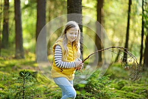 Cute young girl having fun during forest hike on beautiful summer day. Child exploring nature. Active leisure with kids