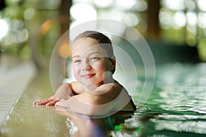 Cute young girl having fun in indoor pool. Child learning to swim. Kid having fun with water toys. Family fun in a pool