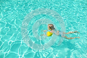 Cute young girl having fun in outdoor pool. Child learning to swim. Kid having fun with water toys. Family fun in a pool. Summer