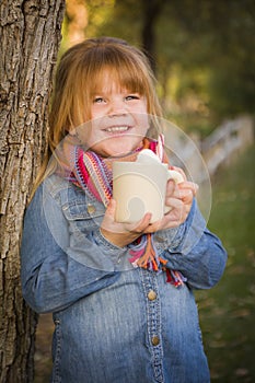 Cute Young Girl Holding Cocoa Mug with Marsh Mallows Outside