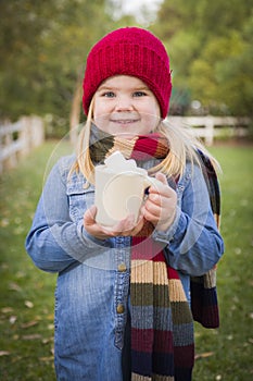 Cute Young Girl Holding Cocoa Mug with Marsh Mallows Outside