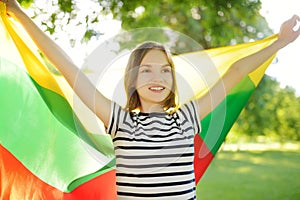 Cute young girl holding tricolor Lithuanian flag on Lithuanian Statehood Day